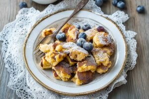 Tiktok scrambled pancakes served in an elegant plate topped with powdered sugar and blueberries