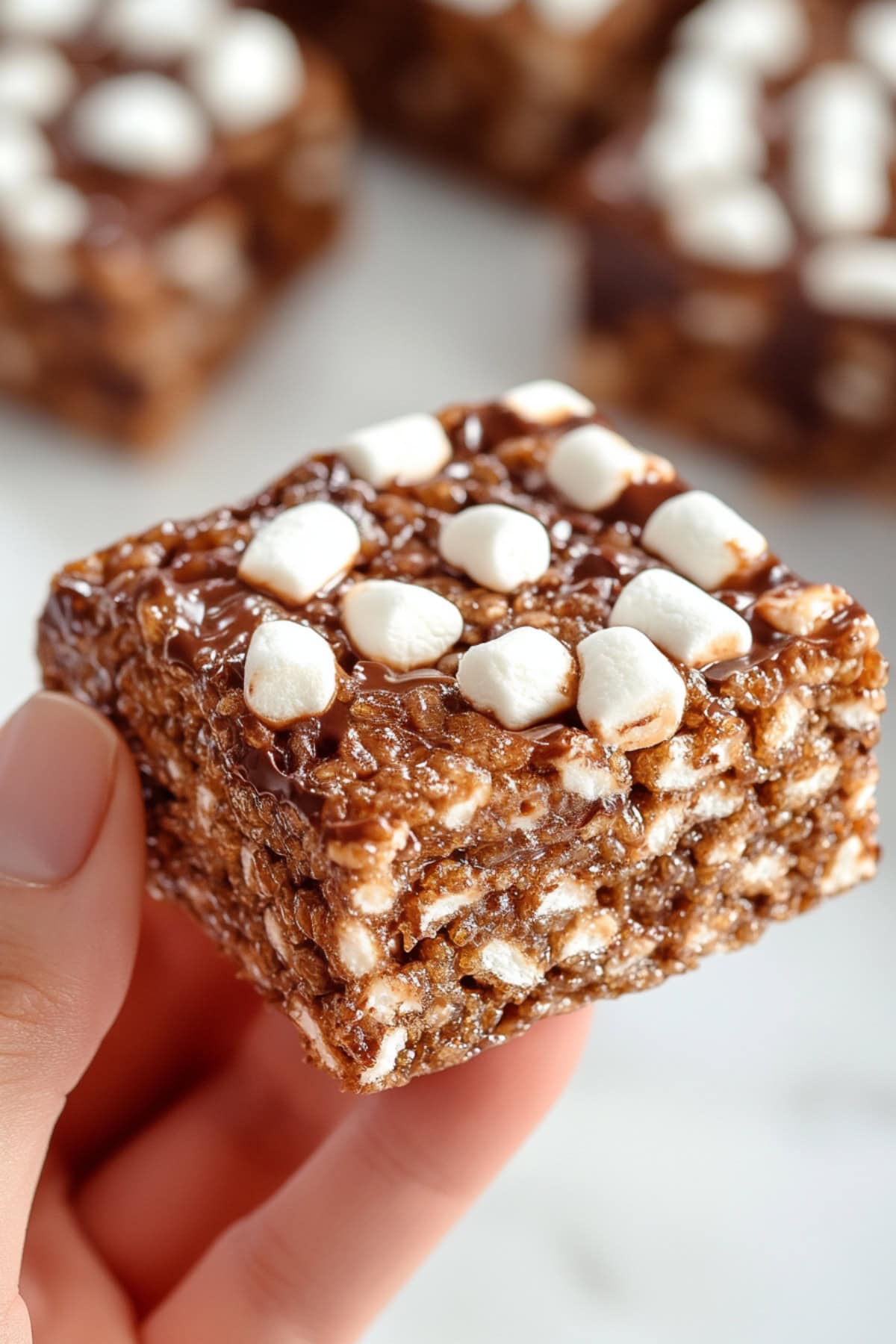 A hand holding rice krispies treats bar with mini-marshmallows