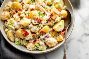 Bacon potato salad coated in a creamy dressing, with onions, eggs and chopped parsley.