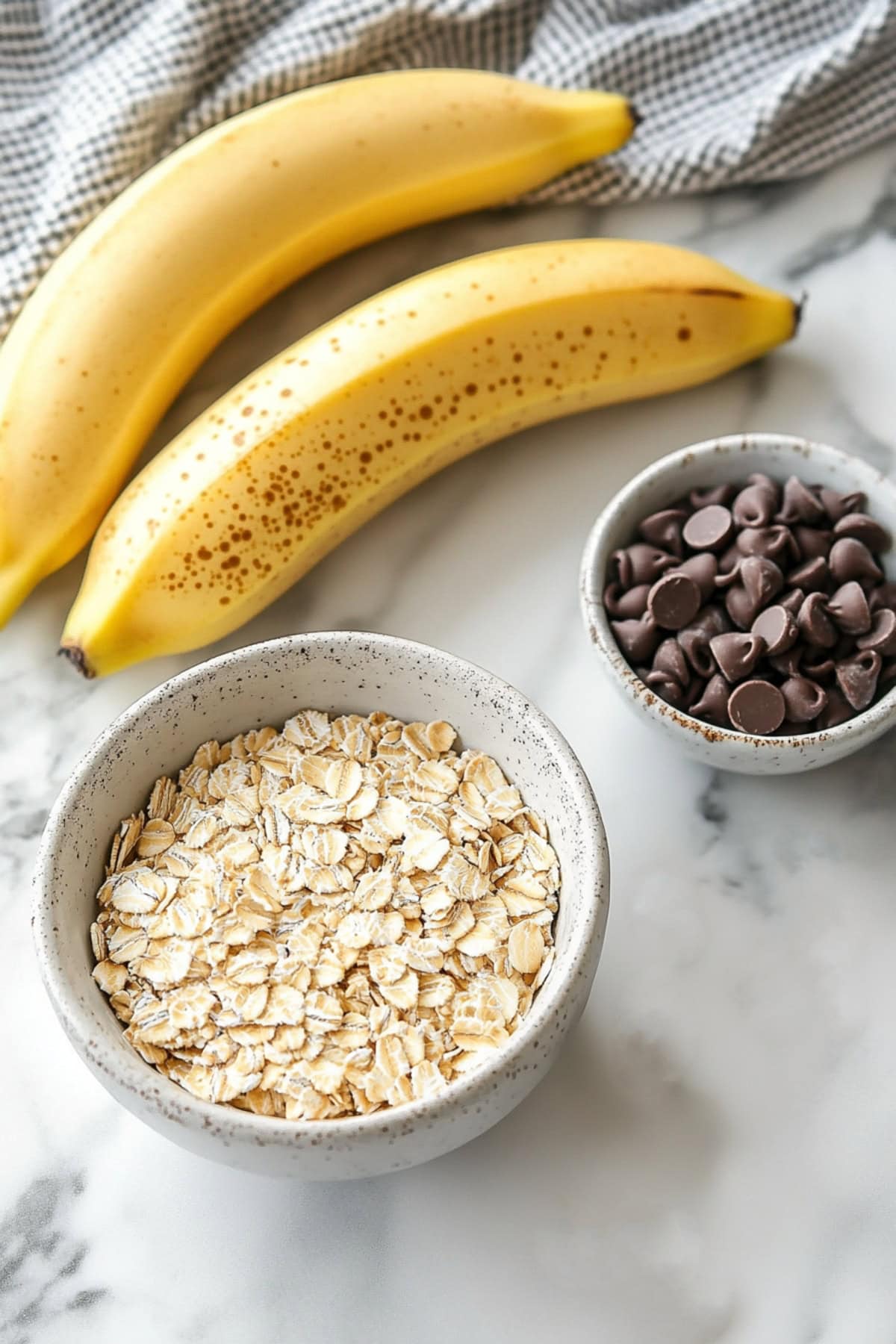 Bananas, oatmeal and chocolate chips on a white marble table
