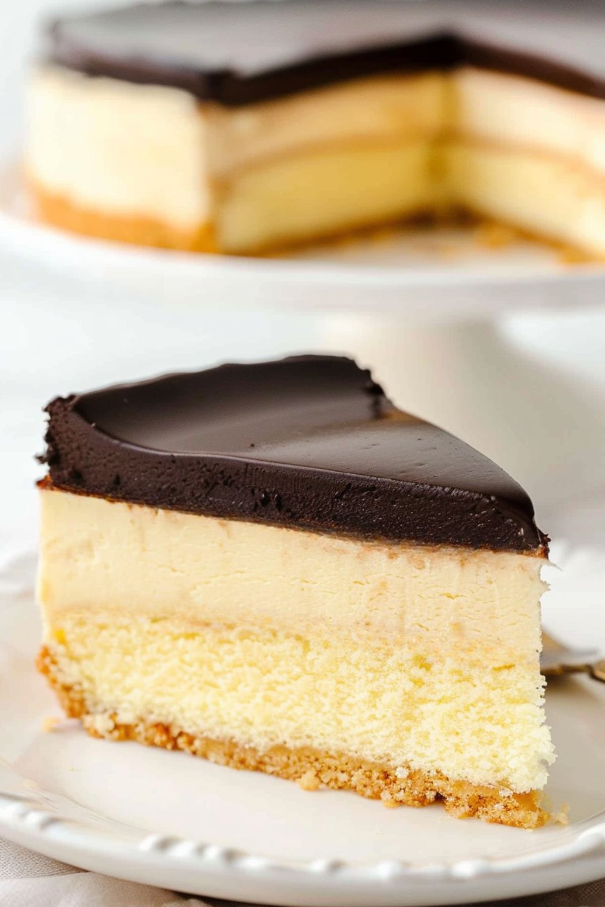 A slice of Boston cream pie cheesecake served on a white plate.
