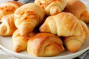 Crescent rolls filled with shredded buffalo chicken inside arranged in a white plate.