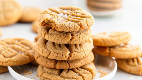Peanut butter cookie stacked on a white plate.
