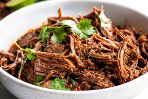 Shredded beef barbacoa served in a white bowl.