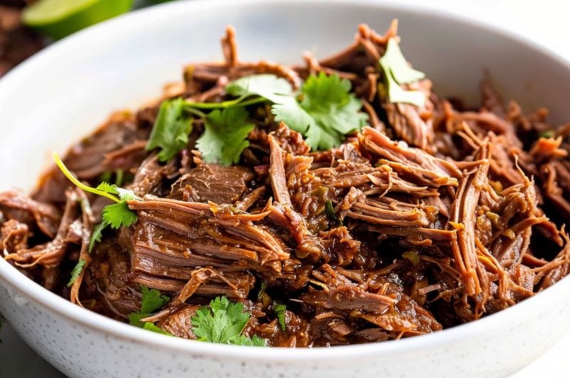 Shredded beef barbacoa served in a white bowl.