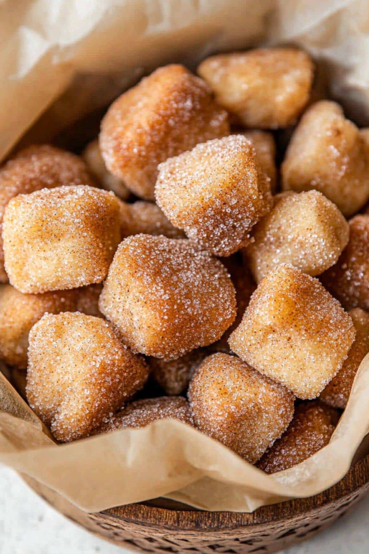 Pretzel bites covered in cinnamon sugar in a basket with parchment paper.