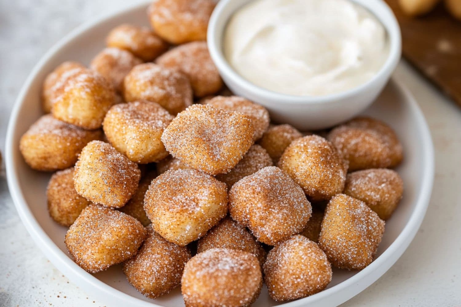 Platter of cinnamon sugar coated baked dough served with cream cheese dip in a small bowl.