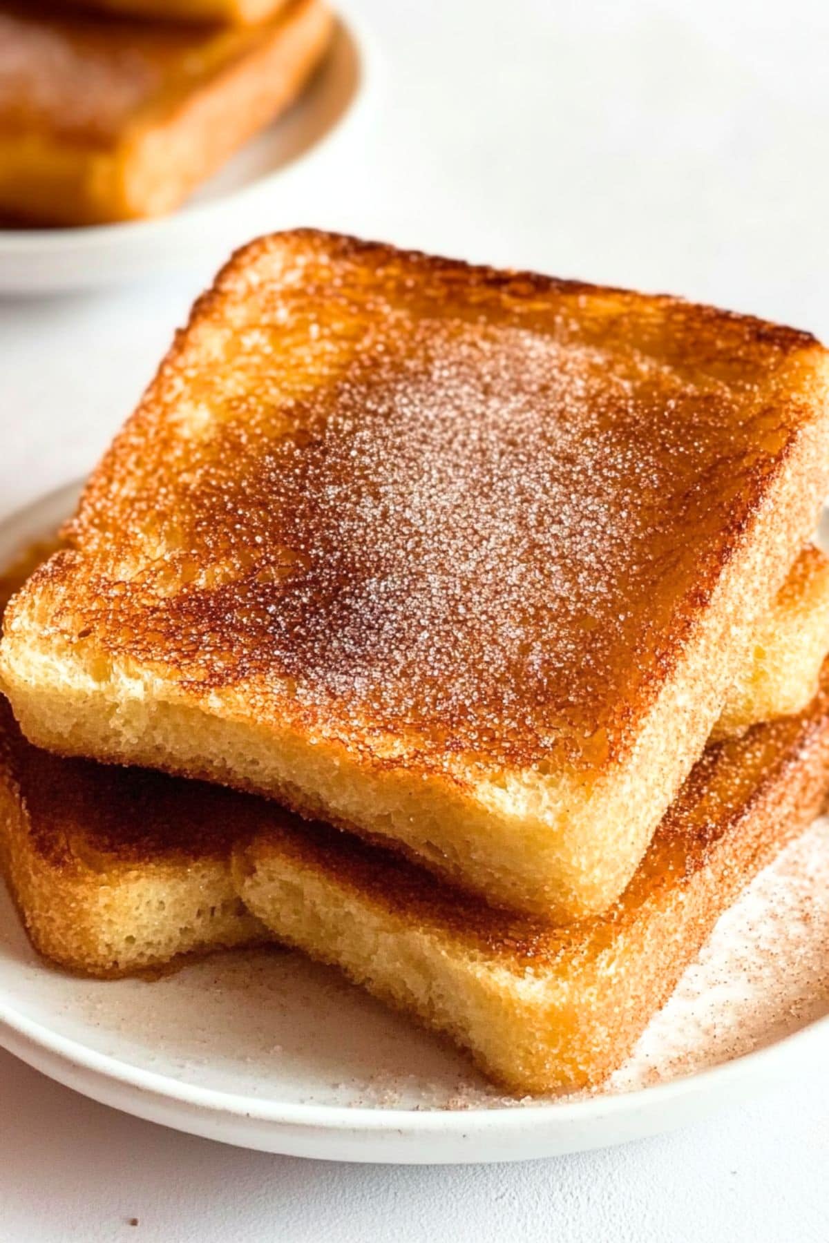 Slices of toast bread with cinnamon sugar served in a white plate.