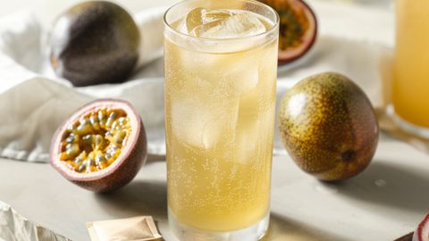 Iced green tea served in glasses with ice sitting next to sliced in half passion fruits..