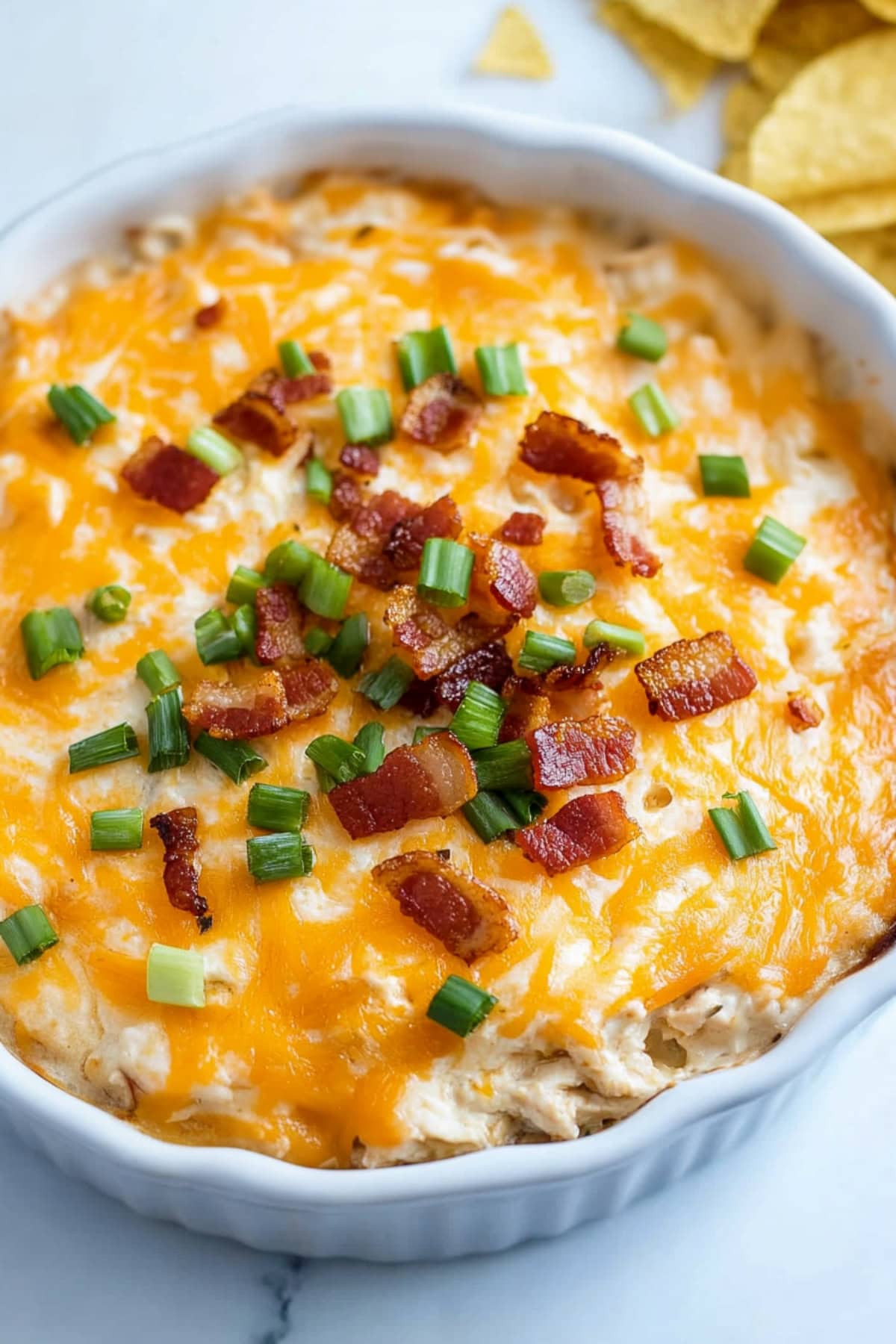 Crack chicken dip with bacon bits and chopped green onions in a ramekin bowl.