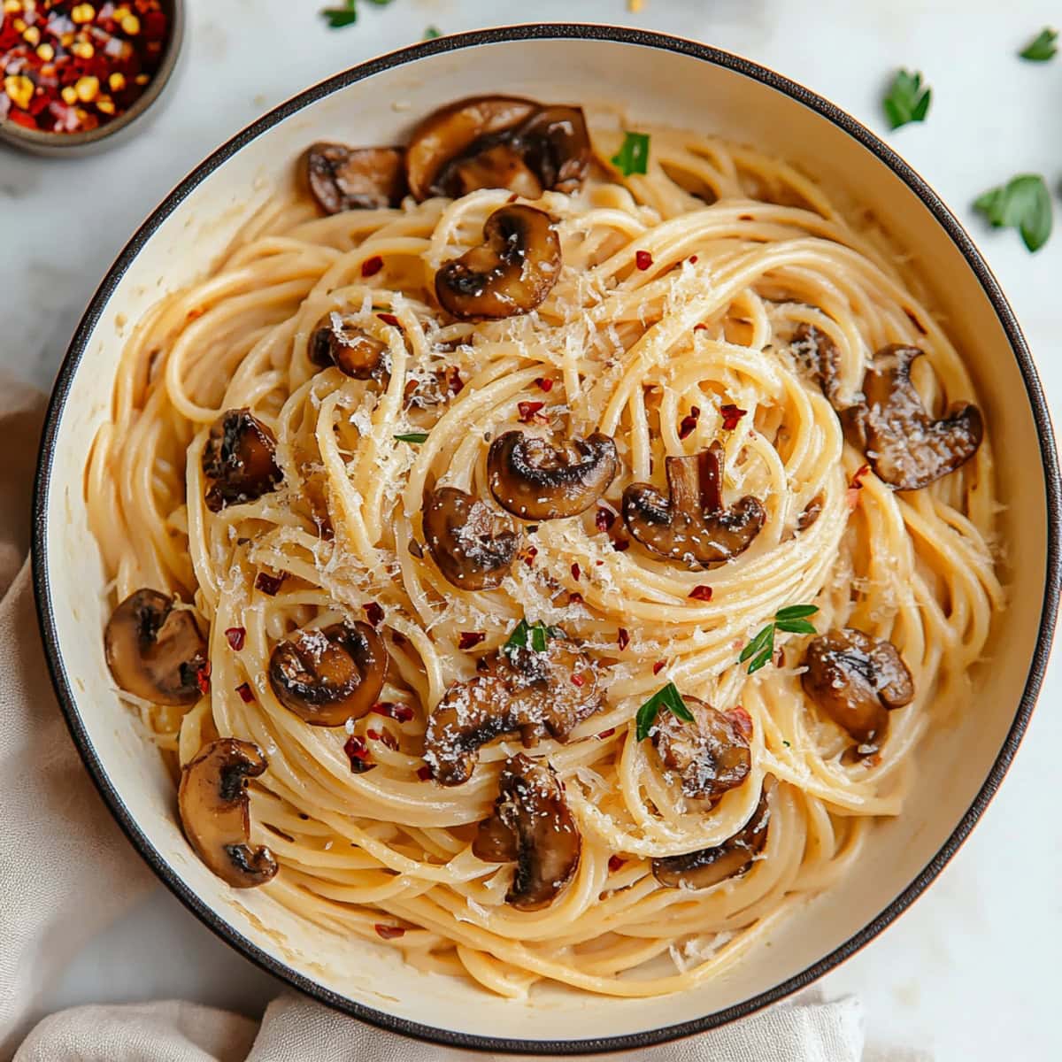 An overhead of creamy miso mushroom pasta with spaghetti, parmesan cheese and red pepper flakes.