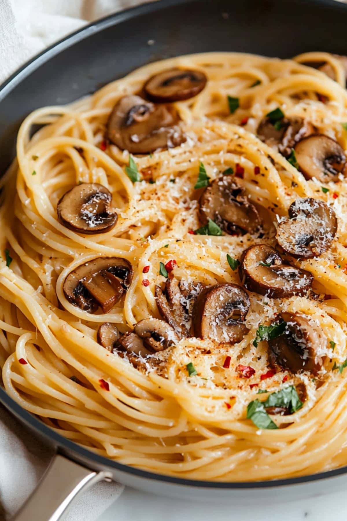 A plate of creamy mushroom pasta topped with fresh parsley and grated parmesan.