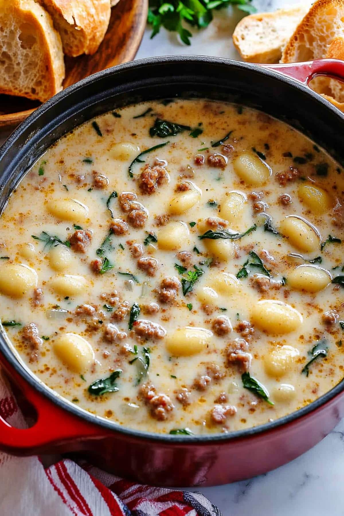 A dutch oven filled with creamy sausage and gnocchi soup, top view