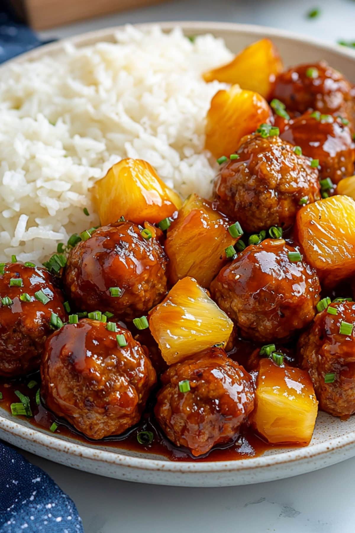 A plate of crockpot Hawaiian meatballs with chunky pineapples in a barbecue sauce.