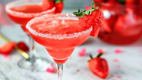 Refreshing strawberry vodka cocktail in a sugar rimmed glass garnished with fresh strawberries.