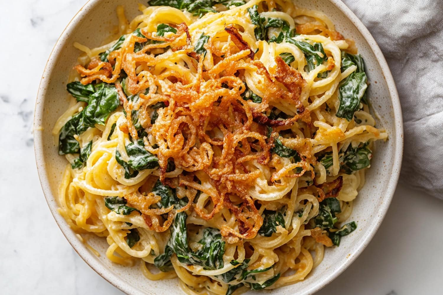 An overhead view of delicious homemade Monterey spaghetti with spinach and fried onions.