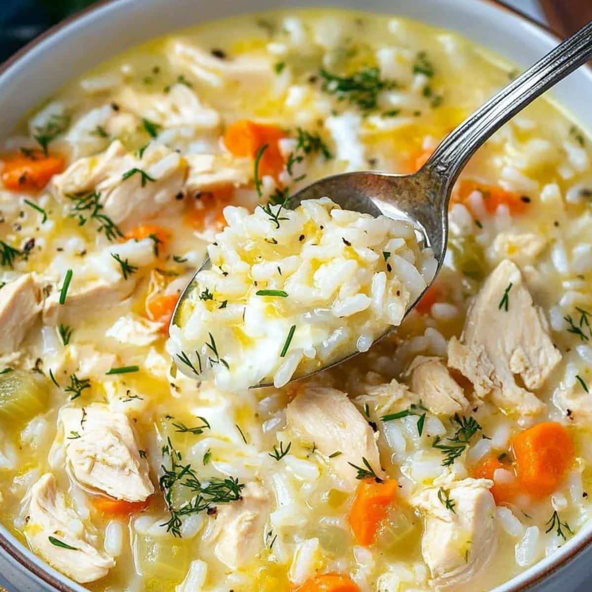Spoon lifting cooked rice from a bowl of Greek lemon chicken soup - 4