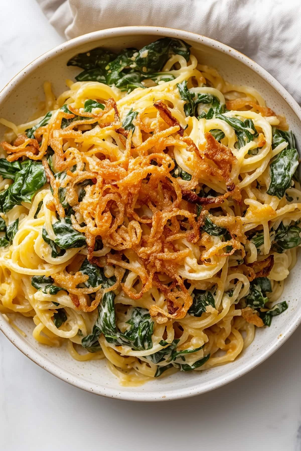 Homemade creamy Monterey spaghetti with fried onions and spinach.