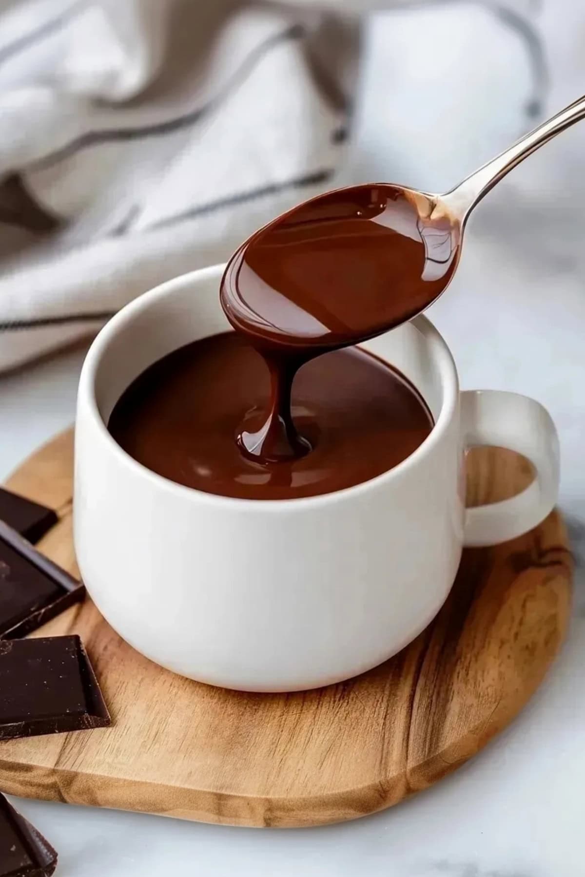 A spoon pouring an Italian hot chocolate into a mug.