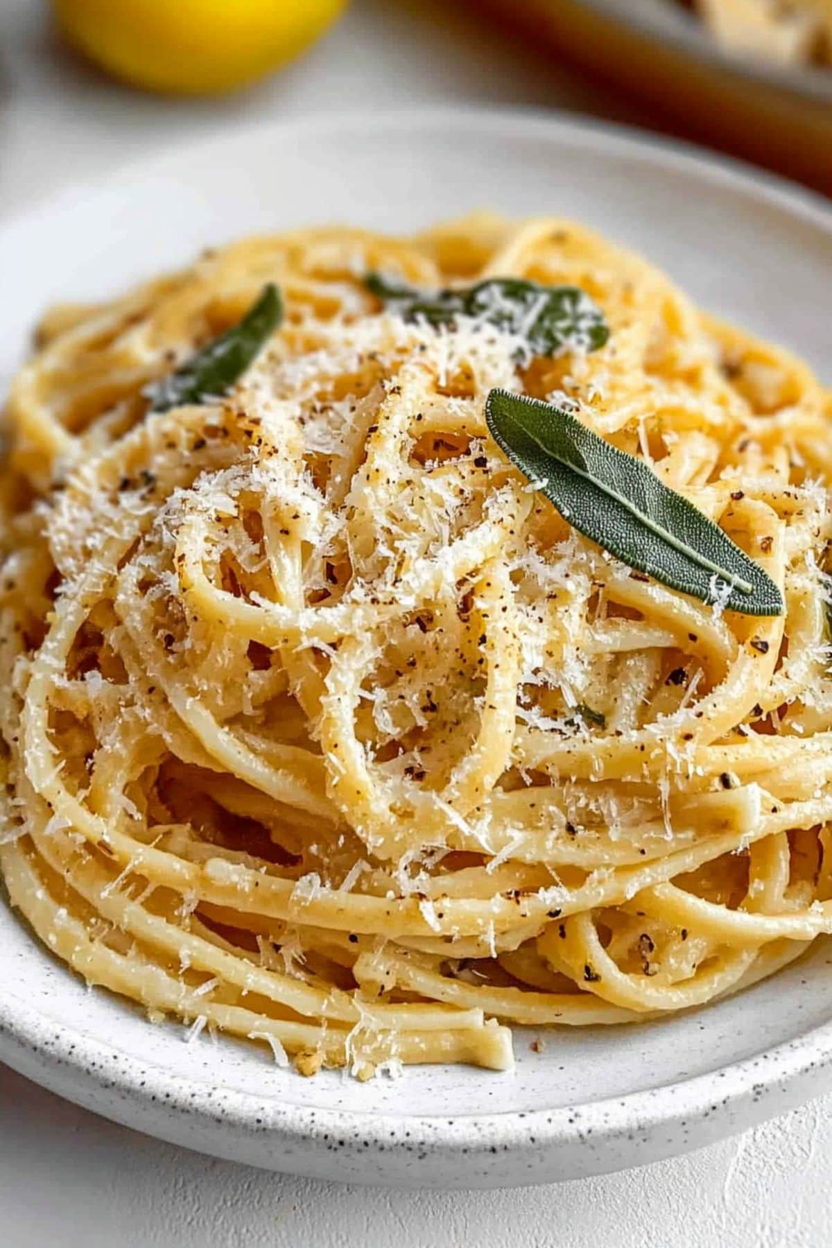 A serving of Jennifer Garner's 5-ingredient pasta served in a white plate garnished with cheese and sage leaves.