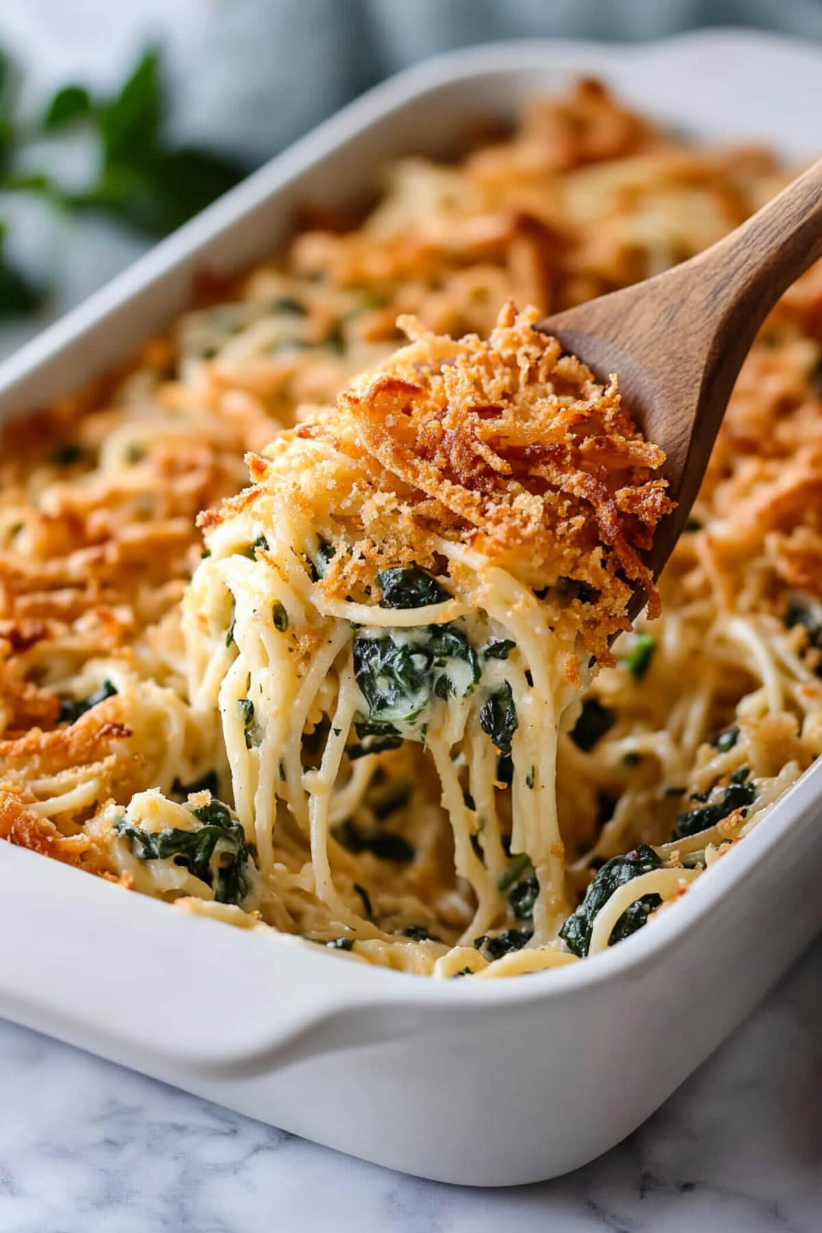 A baking dish filled with Monterey spaghetti with crispy fried onions and spinach.