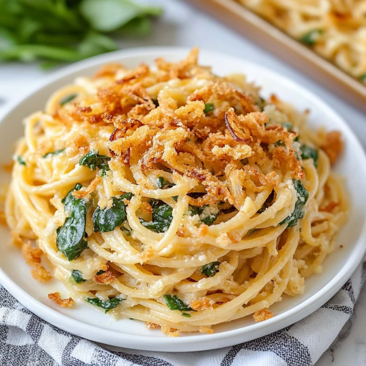 Savory homemade Monterey spaghetti with spinach, topped with fried onions.