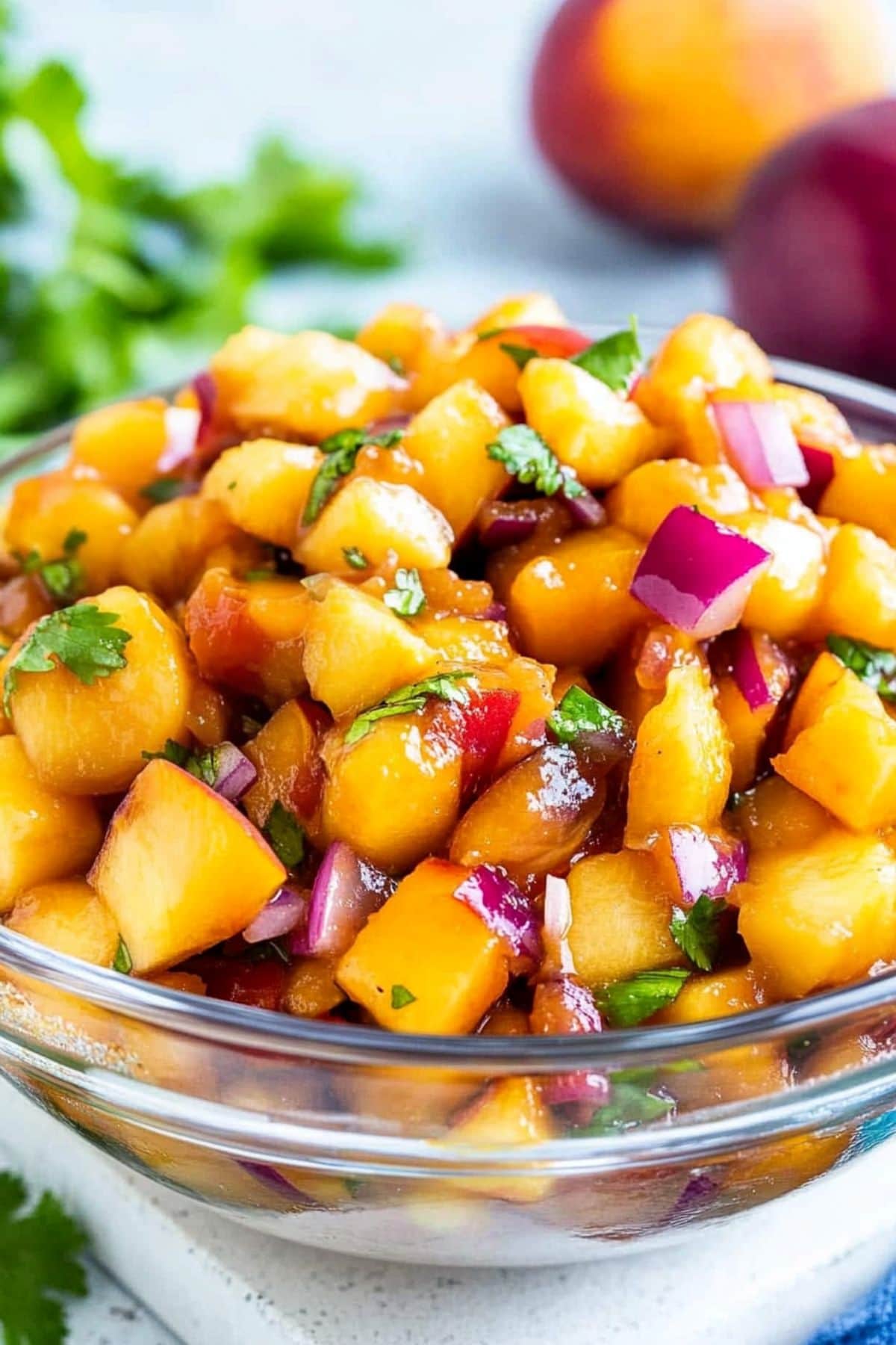 Peach salsa made with peaches, red bell pepper, red onion, and jalapeño in a glass bowl.