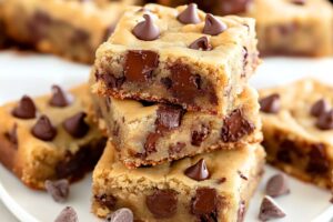 Square slices of peanut butter chocolate chips sitting in a white plate.