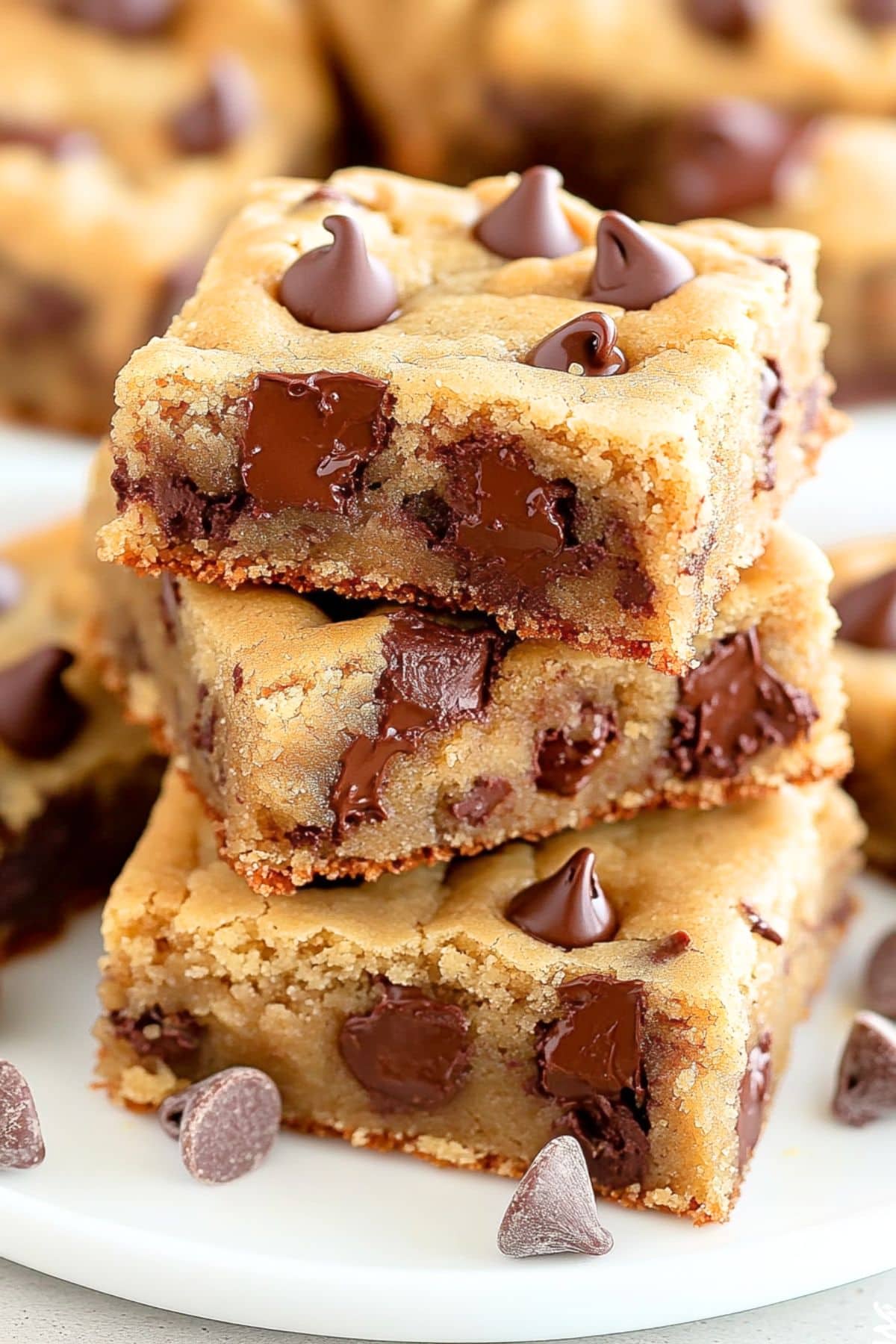 Square slices of chewy chocolate chip and peanut butter cookies stacked on a plate.