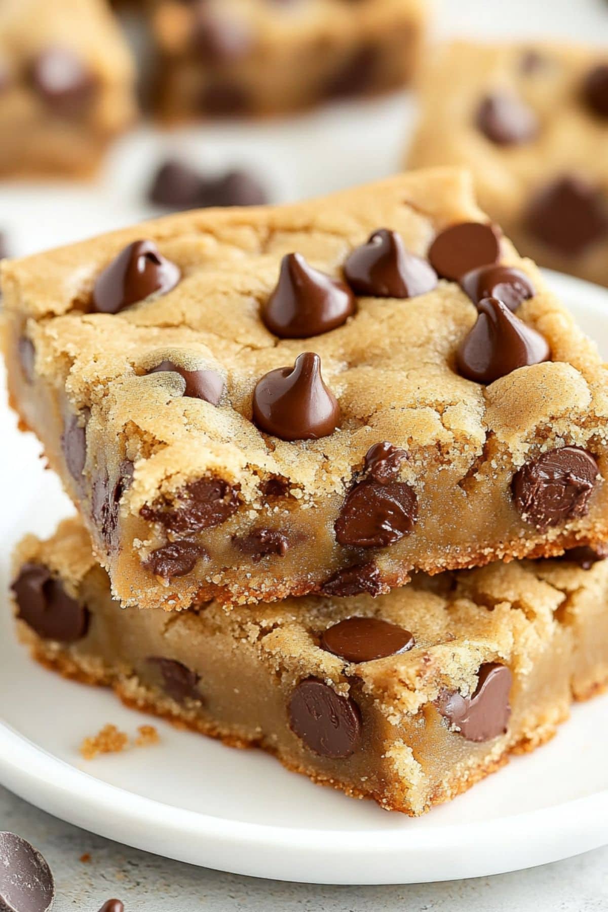 Chocolate chip cookie bars stacked on a white plate.