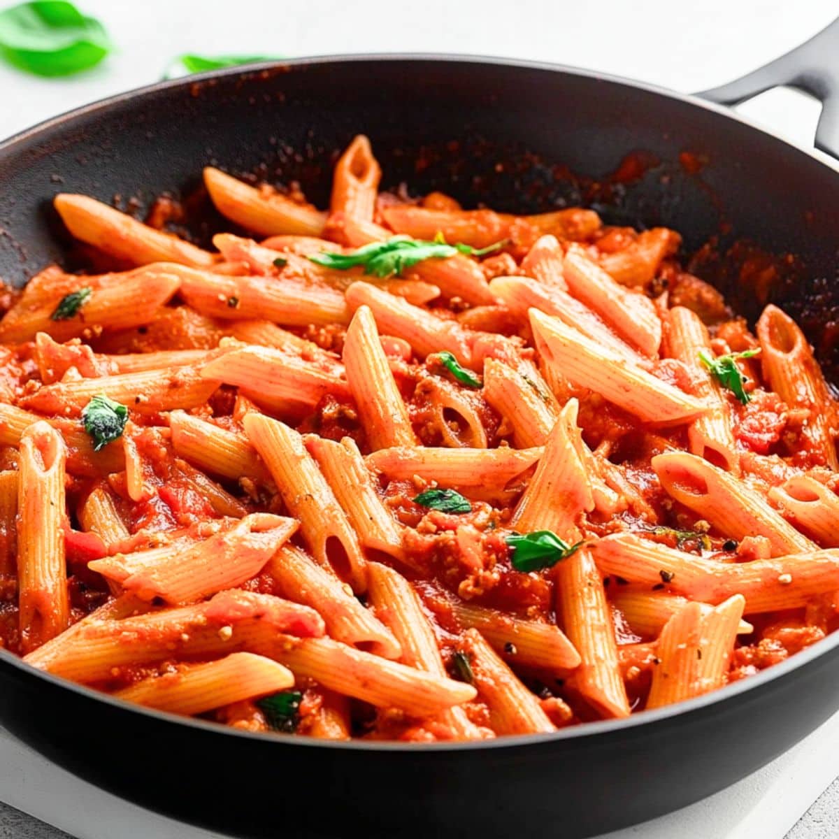 Penne arrabbiatta cooked in a skillet pan in crushed tomato sauce and spices.