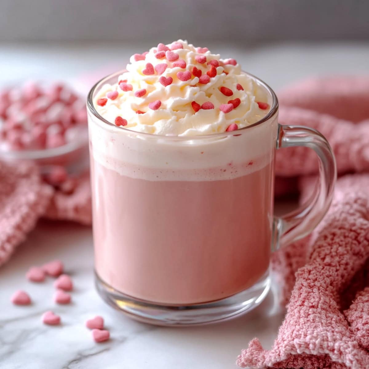 Homemade pink hot chocolate with whipped cream and edible heart-shaped candies.