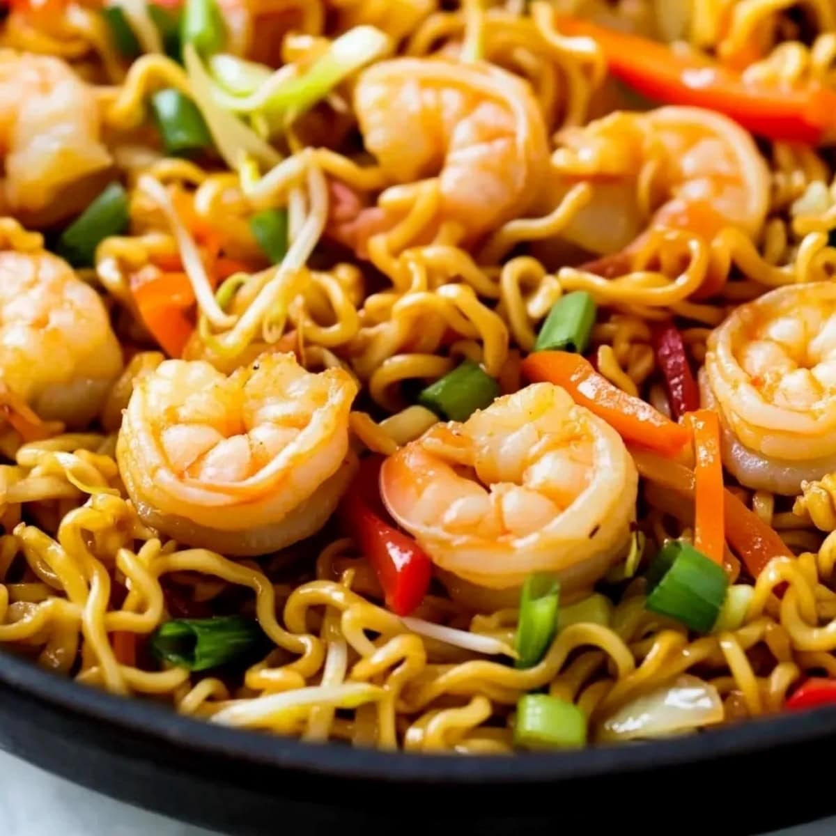 A close-up of shrimp chow mein with vegetables in a skillet.