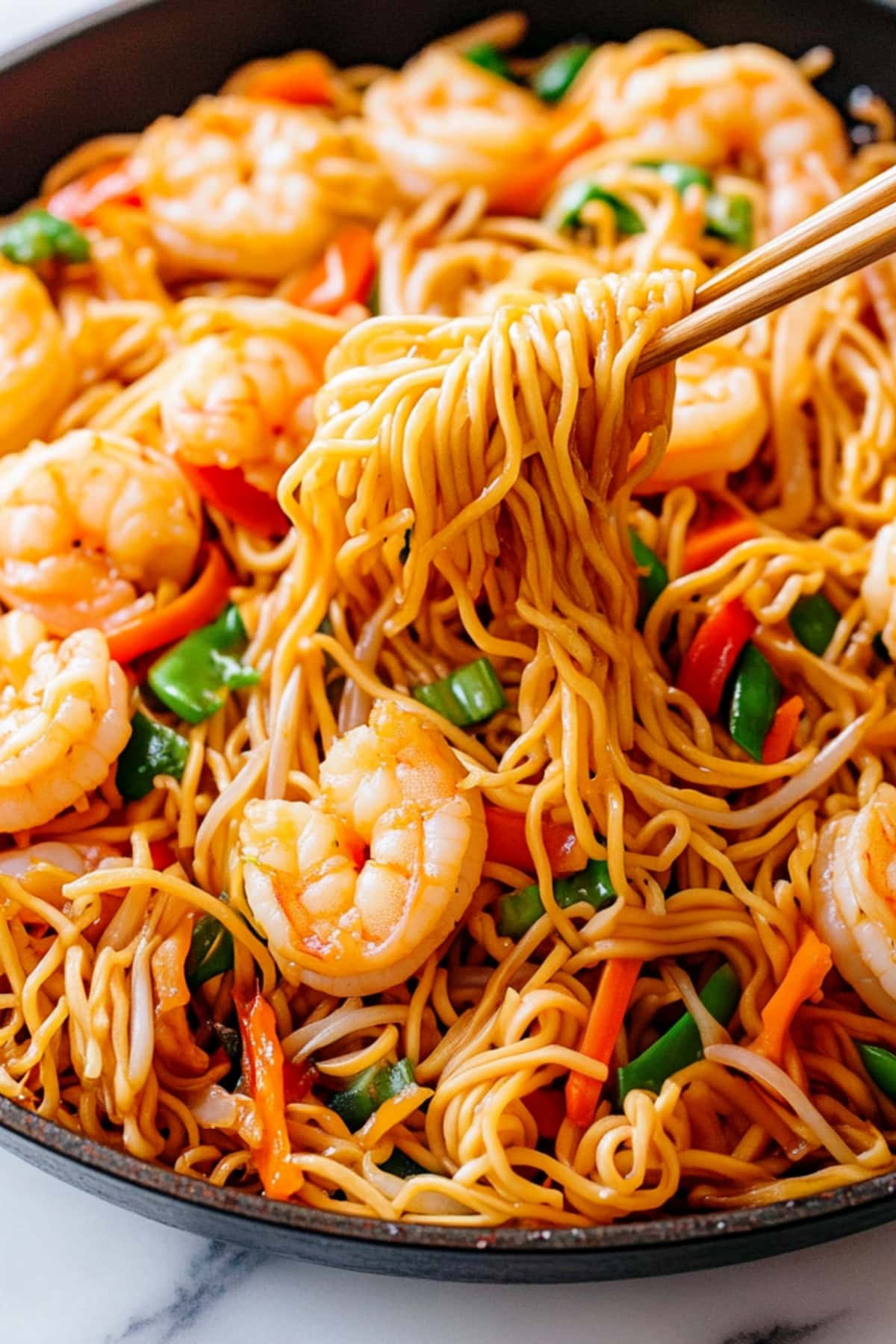 Shrimp chow mein with stir-fry vegetables in a skillet.