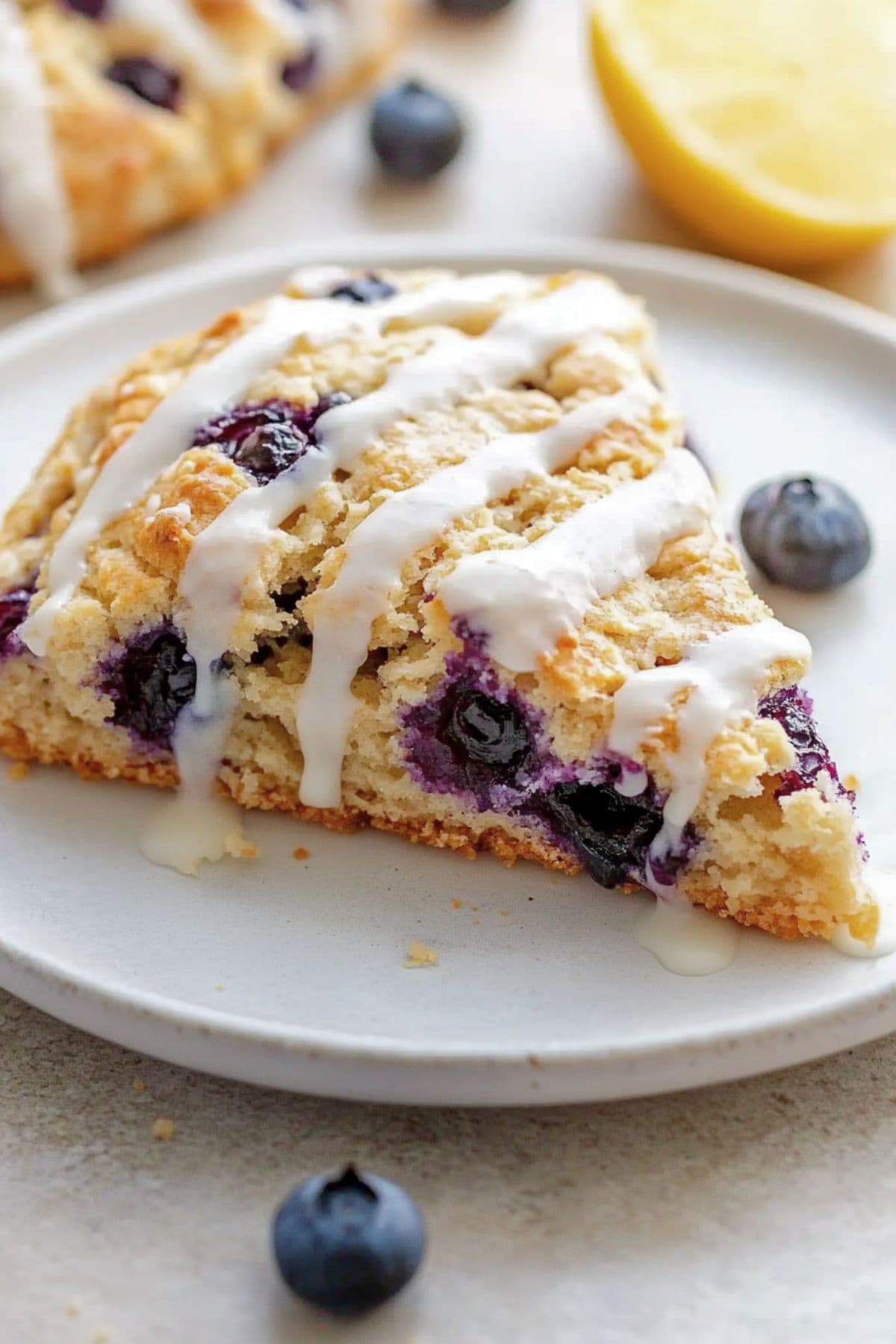 Copycat Starbucks Blueberry scone on a white plate with a drizzle of vanilla glaze