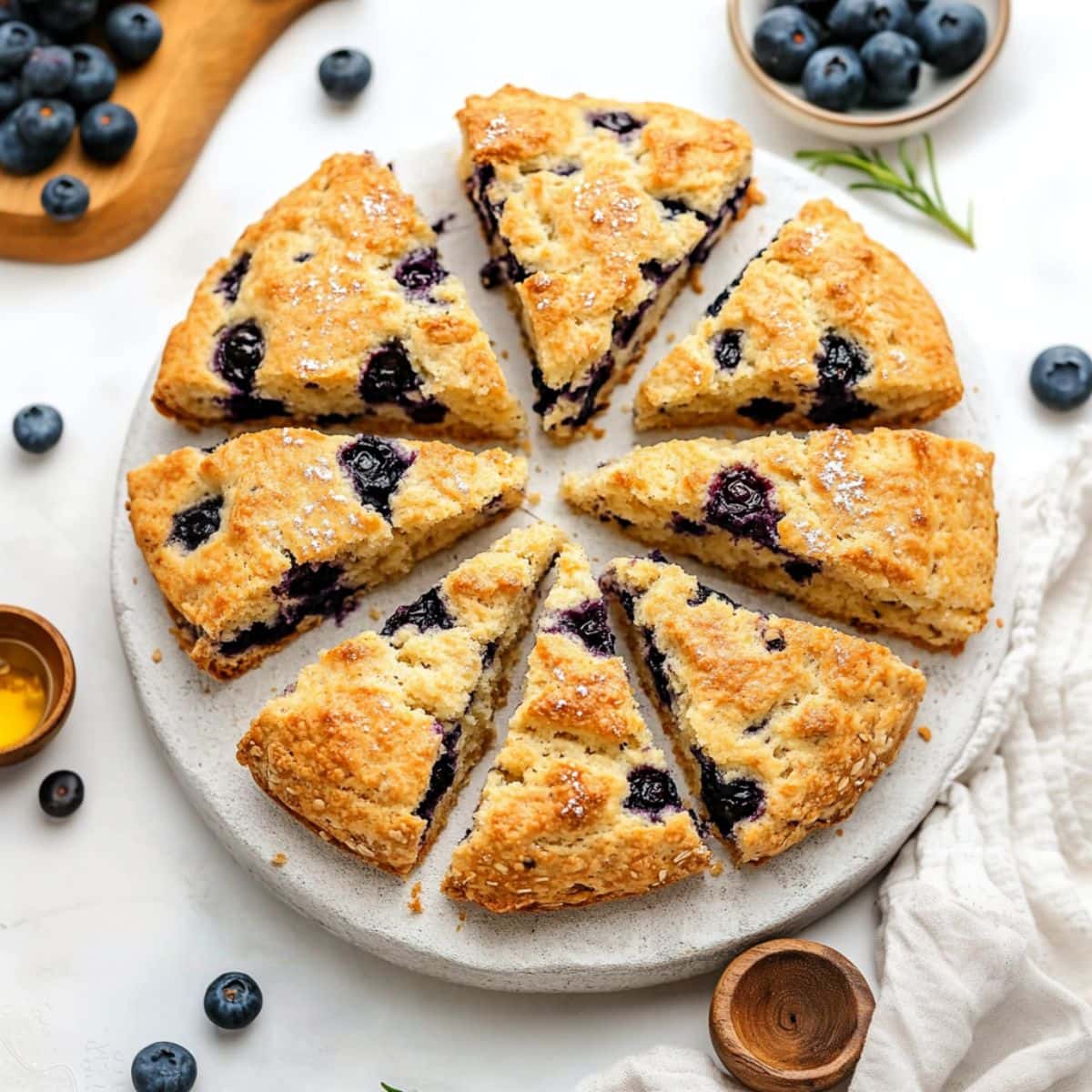 Blueberry scone wedges arranged on top of a white round concrete surface, top view