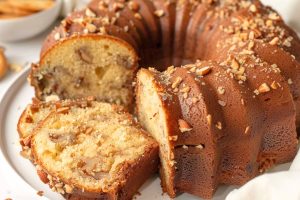 Portion sliced vanilla wafer cake with sprinkles chopped pecans sitting on a cake tray.