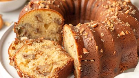 Portion sliced vanilla wafer cake with sprinkles chopped pecans sitting on a cake tray.