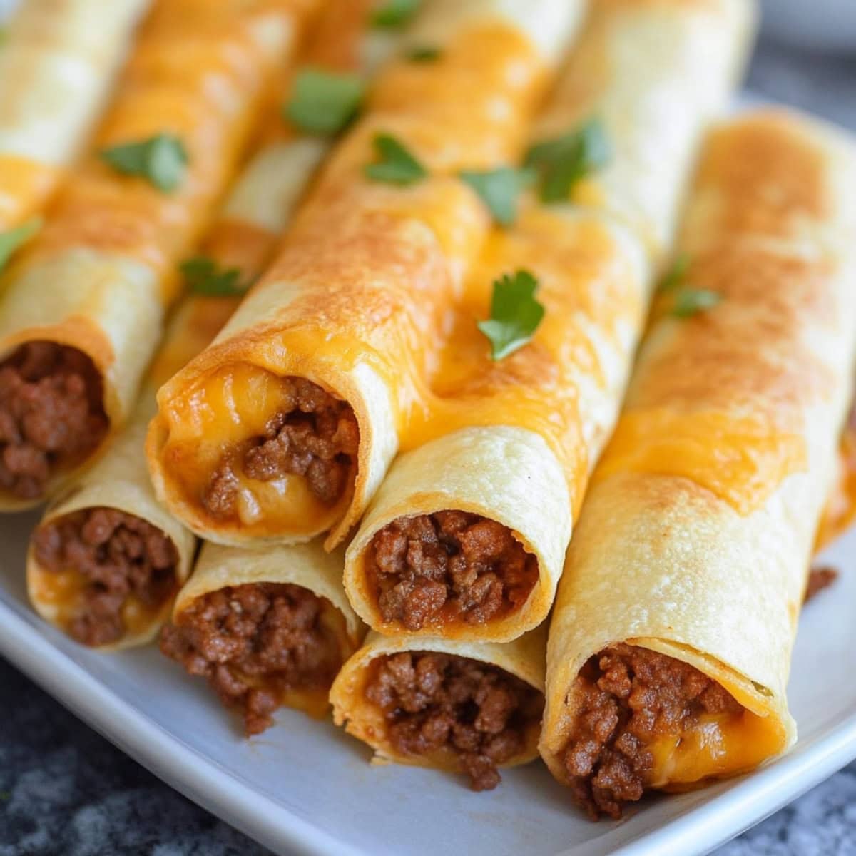 Beef wrapped in corn tortillas covered with melted cheese served in a white plate.