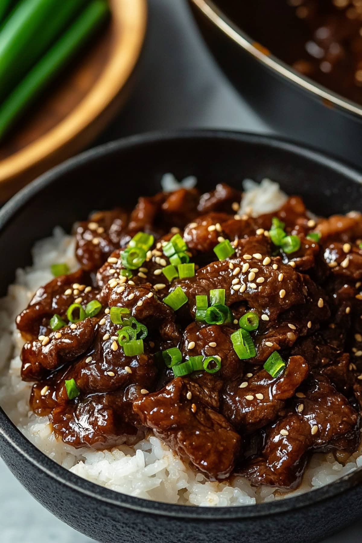 White rice in a black bowl topped with beef teriyaki.