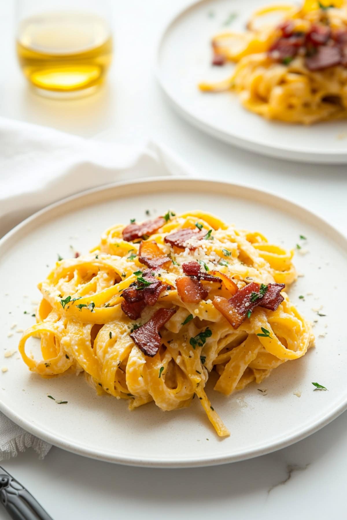 A serving of butternut squash pasta carbonara garnished with chopped bacon.