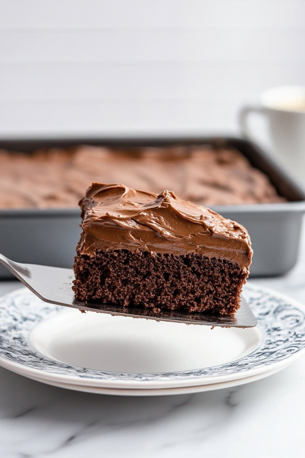 A metal serving spatula holding a slice of chocolate buttermilk cake.