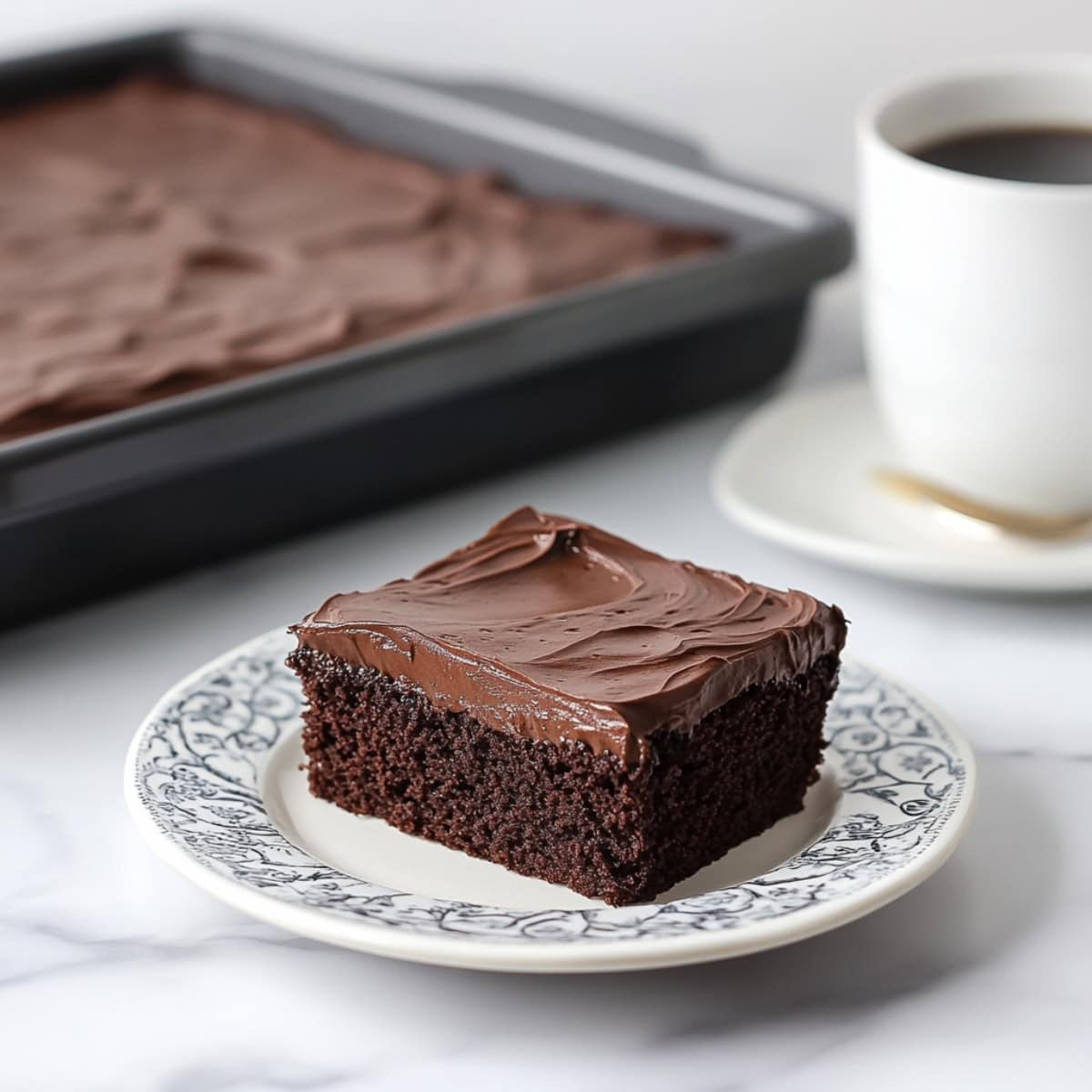 Rich chocolate buttermilk cake with  buttermilk frosting on an elegant plate with coffee on the side