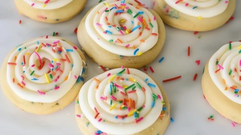 Freshly baked Crumbl birthday cake cookies, decorated with rainbow sprinkles and a smooth swirl of frosting.