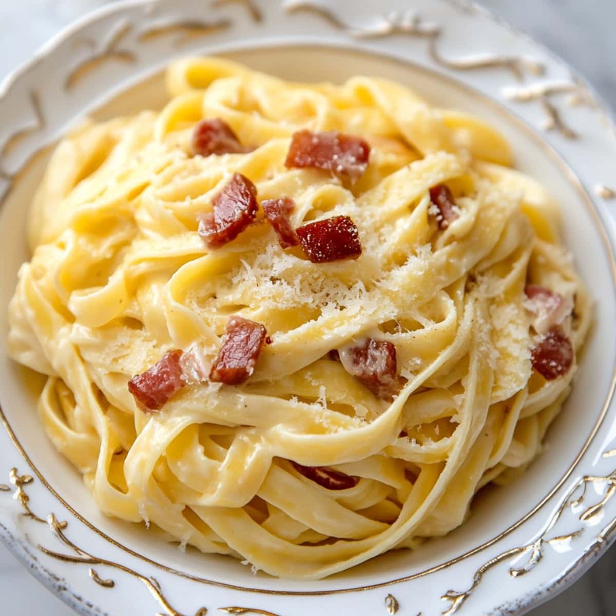 A close-up of fettuccine carbonara, with silky pasta coated in a creamy sauce, topped with black pepper and grated Parmesan.