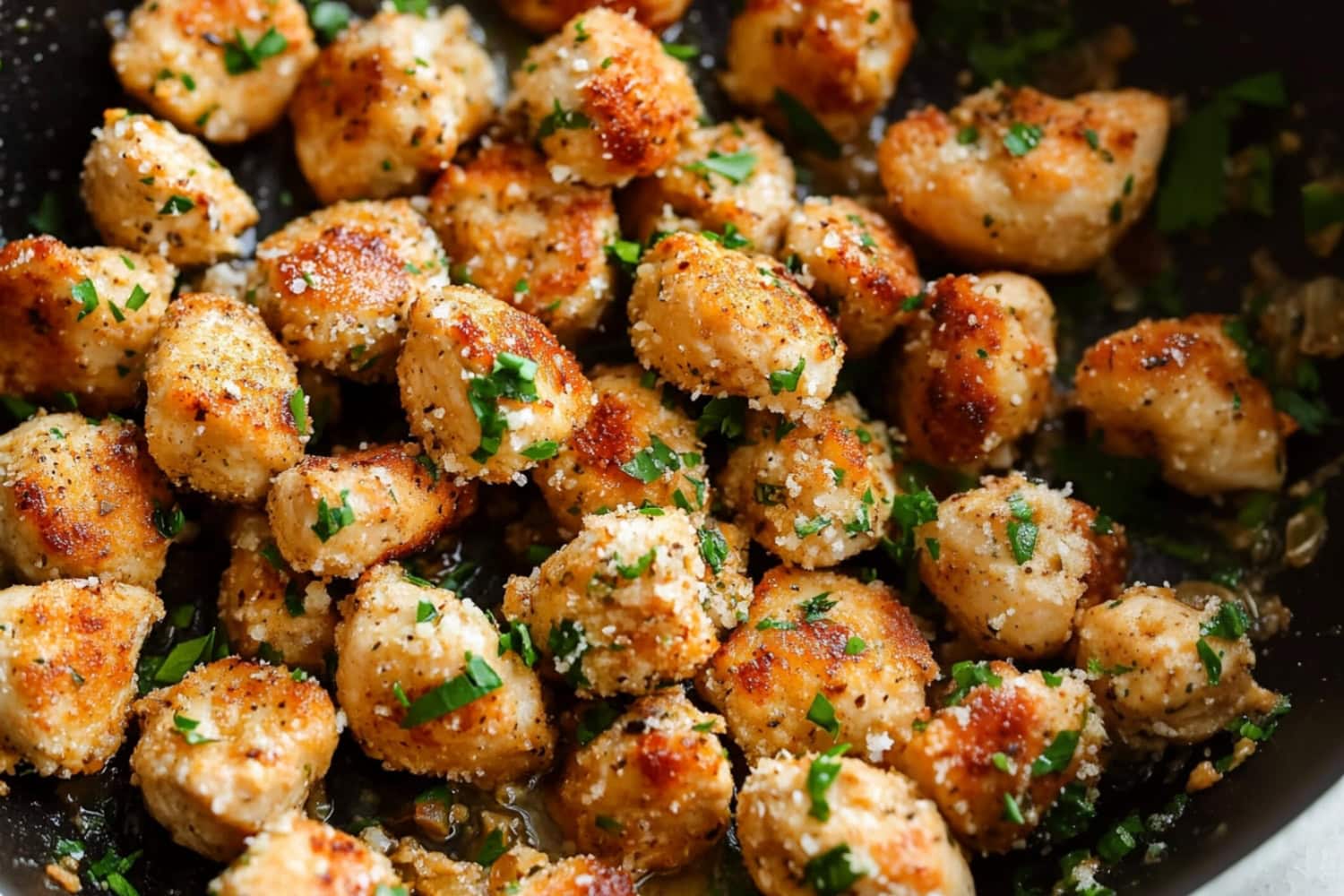 Homemade appetizing garlic parmesan chicken bites in a skillet.