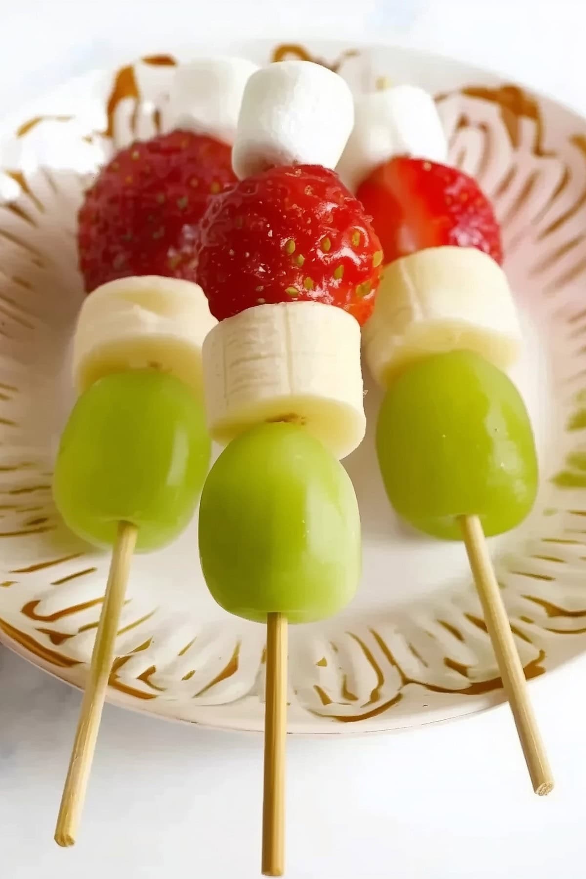 Grinch kabobs with green grapes, strawberries, marshmallows, and banana slices