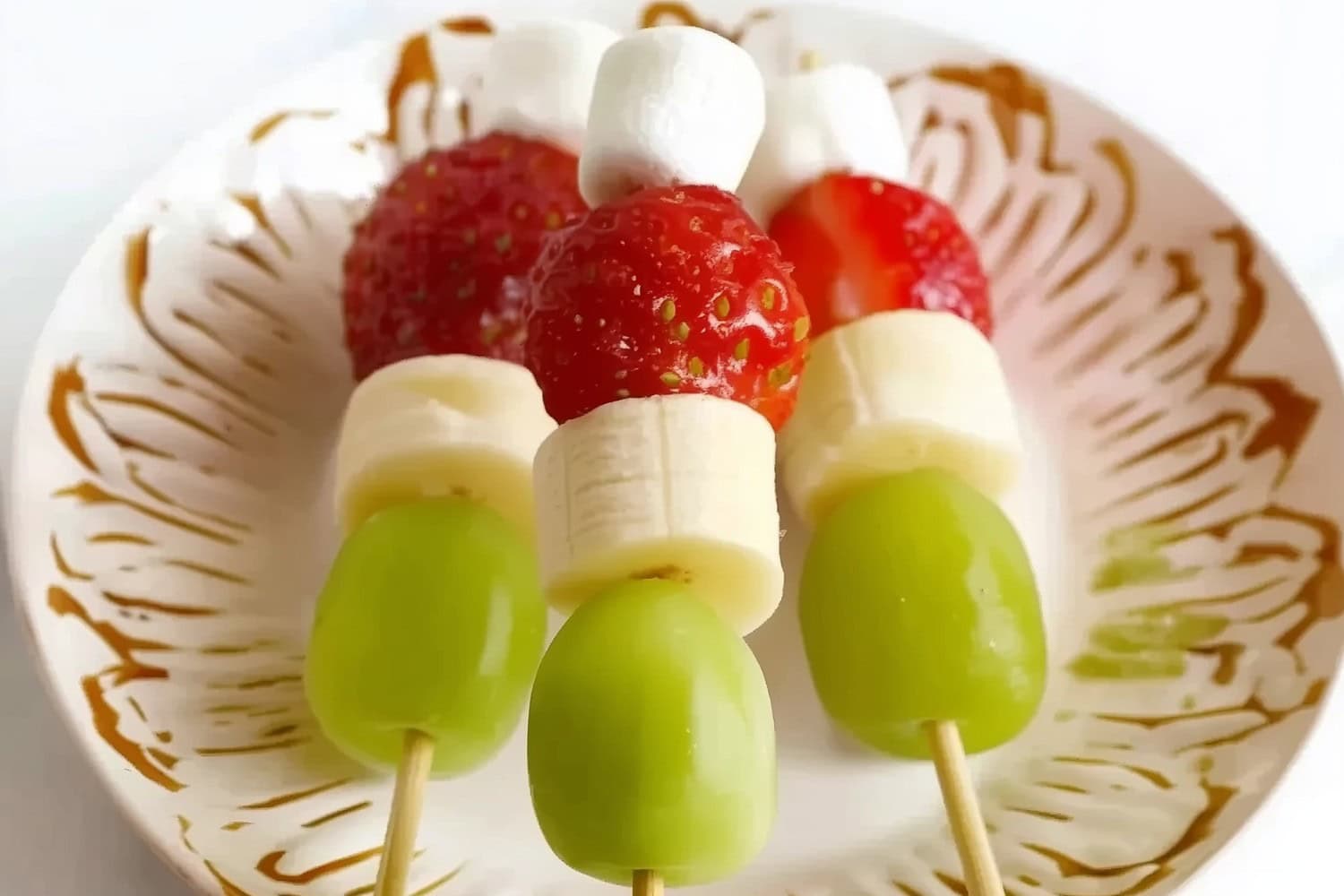 Grinch kabobs with green grapes, strawberries, marshmallow and banana slices.