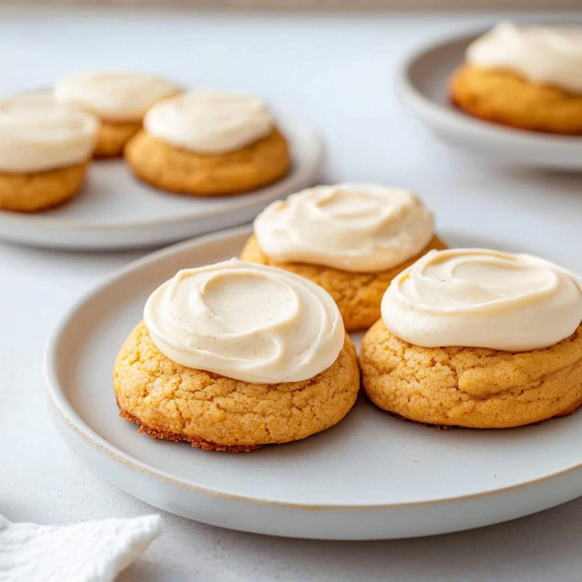 Pumpkin cake mix cookies with cream cheese frosting on a plate.