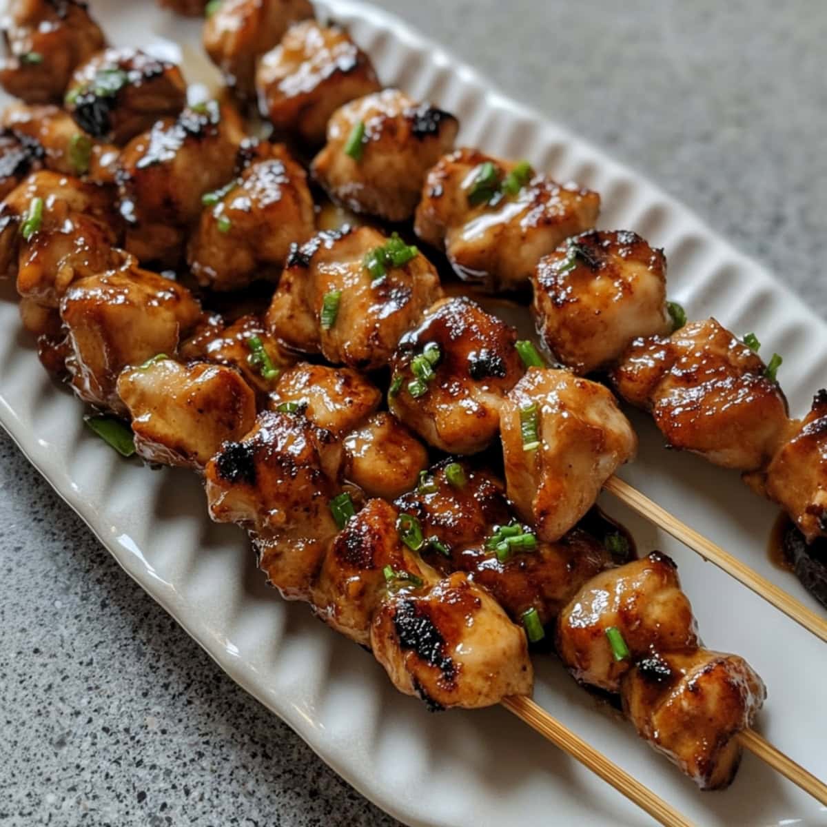 A serving of grilled teriyaki chicken skewers on a plate